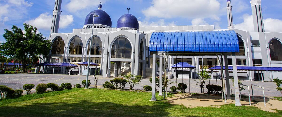 A mosque with two large domes, a minaret, and a covered entrance.