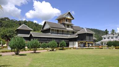 A traditional building with a multi-tiered roof and a tower, surrounded by a well-maintained lawn and trees.