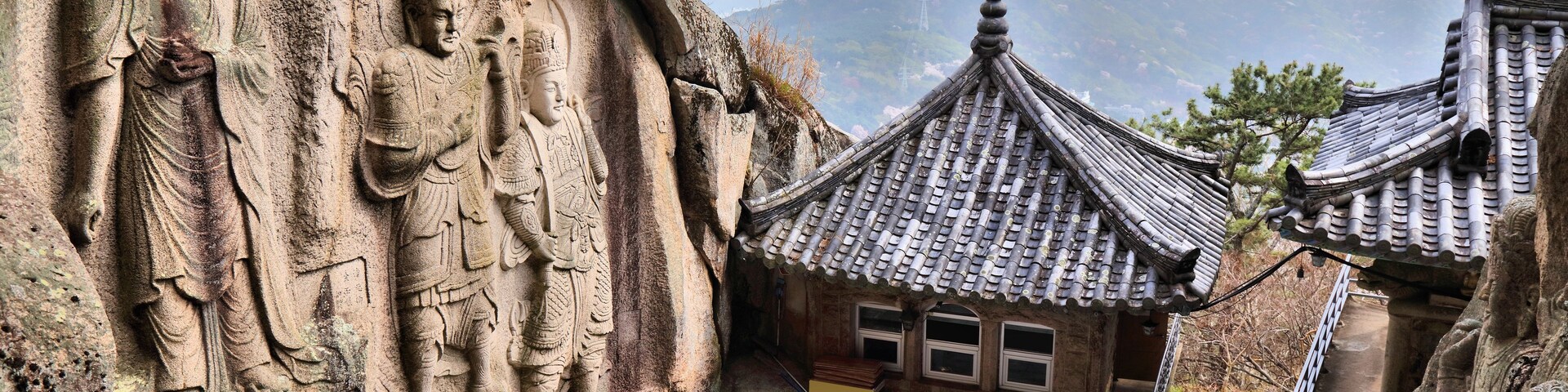 A temple with stone carvings and a traditional tiled roof.