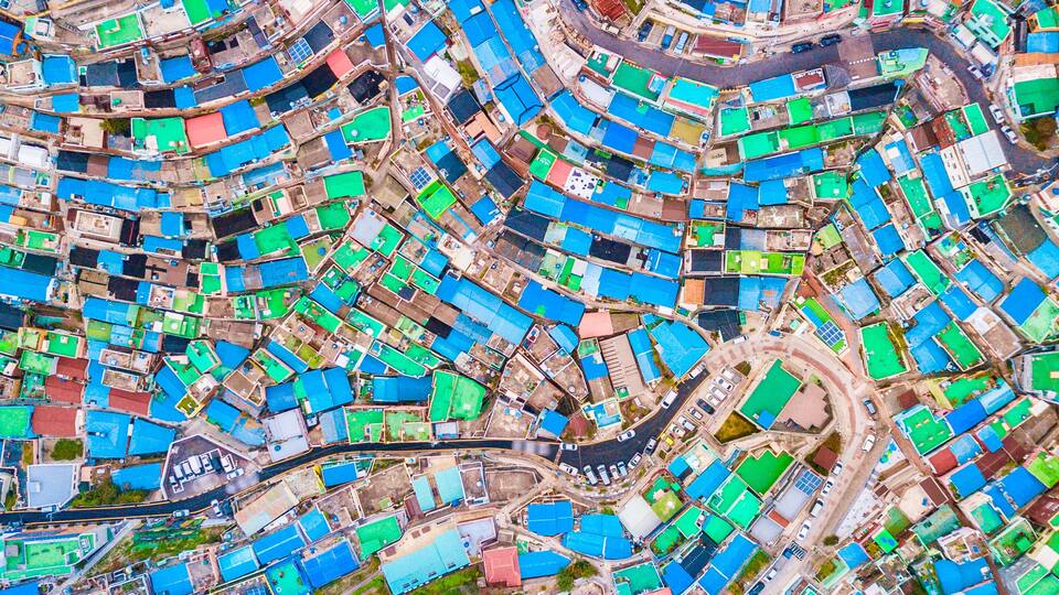 An aerial view of a densely packed urban area with numerous buildings, roads, and green spaces.