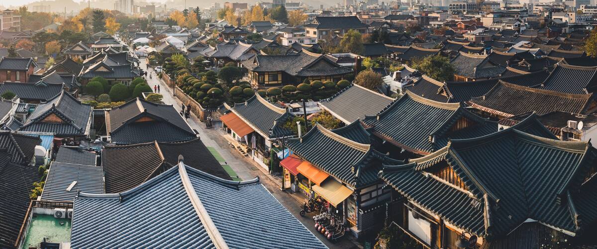 A traditional village with numerous buildings featuring dark, curved roofs.