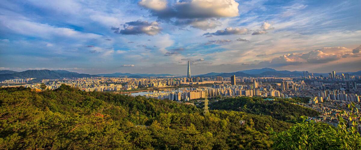 A cityscape with a prominent tower, dense urban buildings, and a mountainous backdrop.