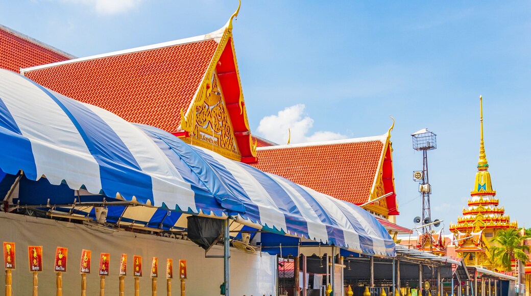 A traditional Thai temple with a red tiled roof and golden decorations.