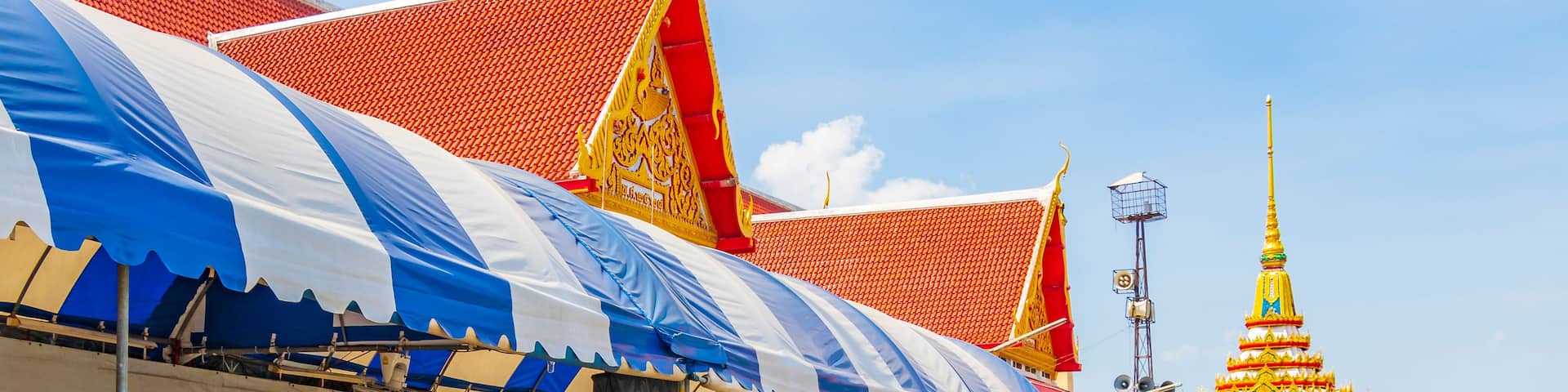 A traditional Thai temple with a red tiled roof and golden decorations.