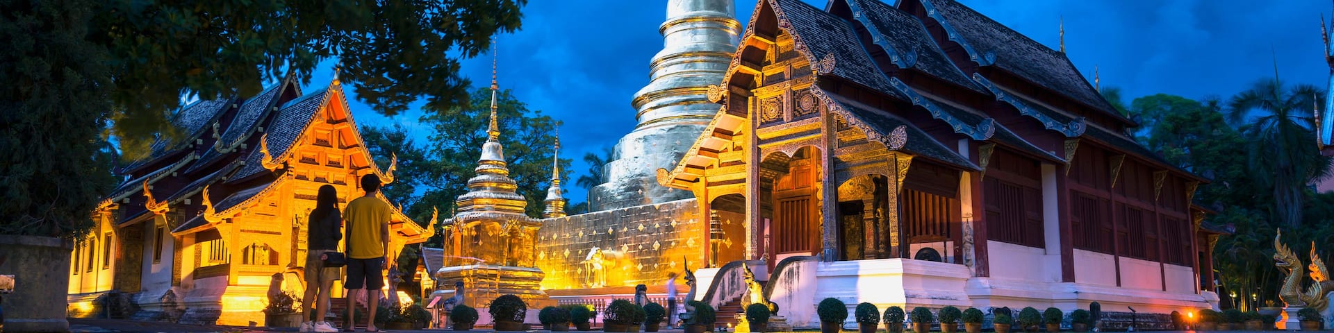 A temple complex with a large stupa and traditional architecture, reflecting in a calm body of water.