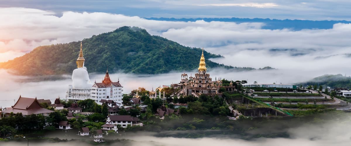 A mountainous landscape with a temple and a white building surrounded by greenery.