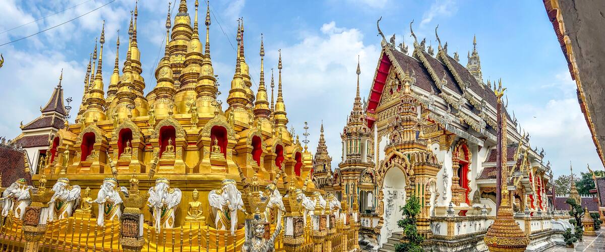 A golden temple with multiple spires and statues, and a white building with red accents.