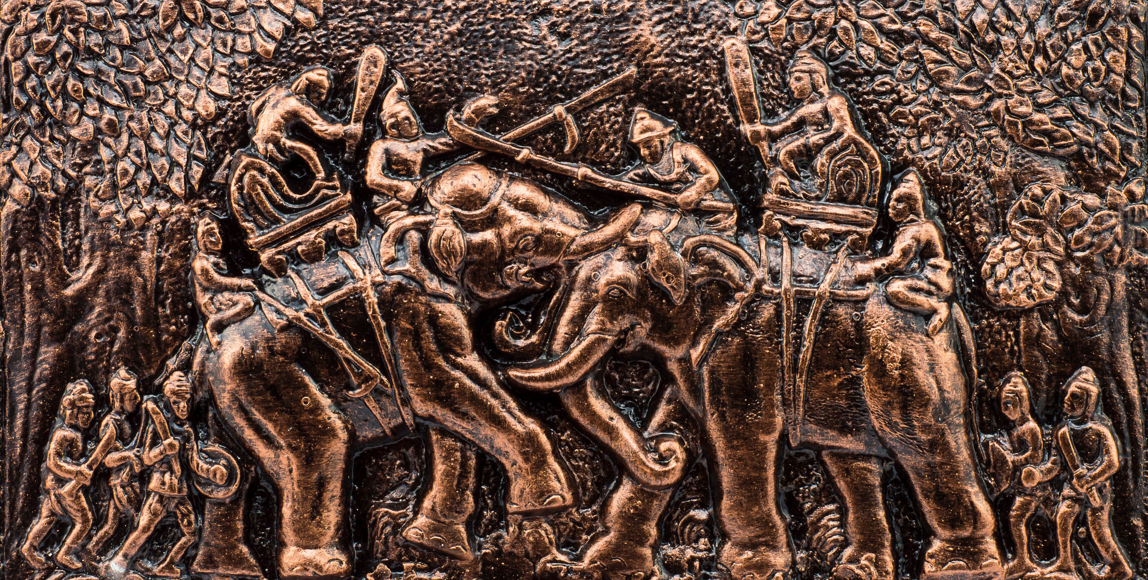A detailed relief sculpture of a battle scene with warriors and elephants.