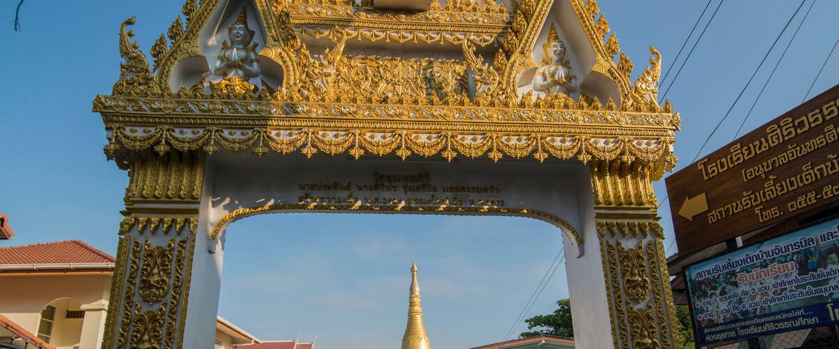 A golden ornate gateway leading to a large golden stupa.