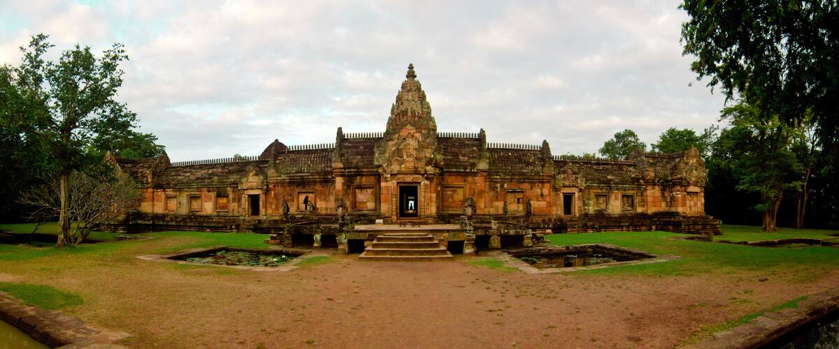 An ancient temple with a central tower, surrounded by a moat and a well-maintained lawn.