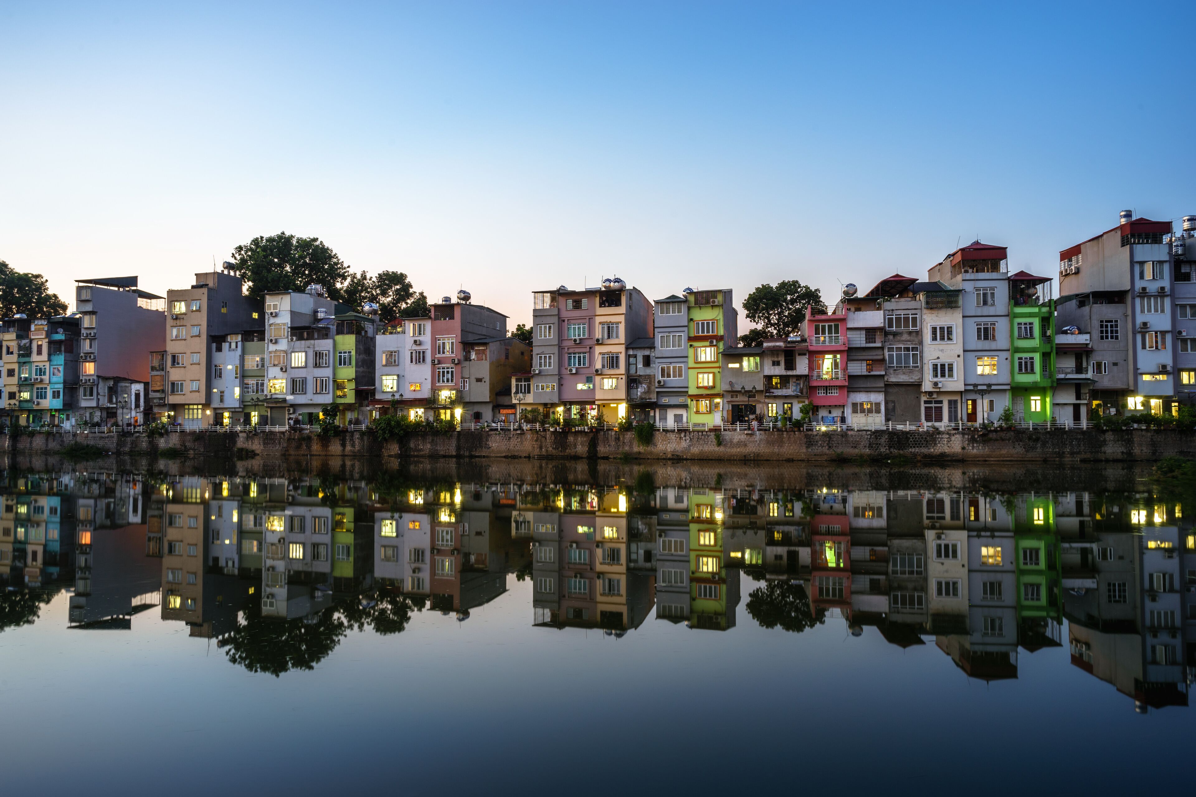 A row of colorful buildings reflected in calm water during twilight.