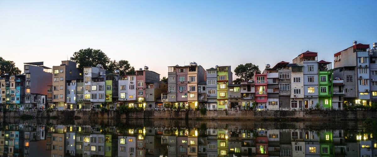 A row of colorful buildings reflected in calm water during twilight.