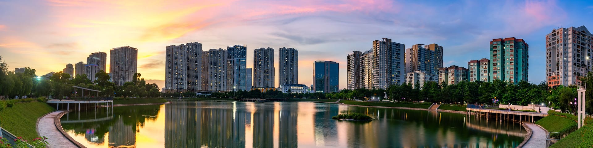 A cityscape with high-rise buildings, a calm lake, and a park with flowers.