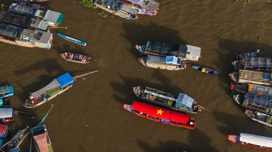 Vista aérea de un río con numerosos barcos amarrados a orillas, algunos con toldos y otros abiertos.