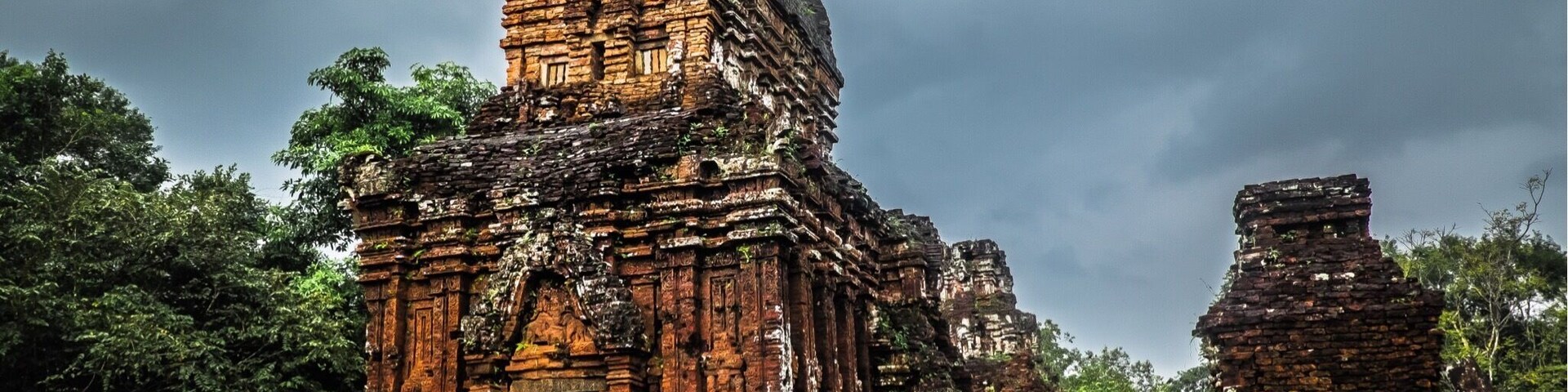 Mỹ Sơn is a about an hours drive from Hoi An and is surround by mountain ranges and dense tropical jungle. It is a collection of Hindu temples constructed between the 4th and the 14th century AD and dedicated to the god Shiva.
It is surprising any of the temples are still standing when you see the size of the nearby bomb craters. The United States heavily bombed the site at the start of the Vietnam war as they suspected the VC of hiding in the temples.
The weather gods were definitely not happy the day we visited which added to the eerie feeling at the site. You could almost hear the whispers of the long extinct civilisation as if they still went about praying to their God.
