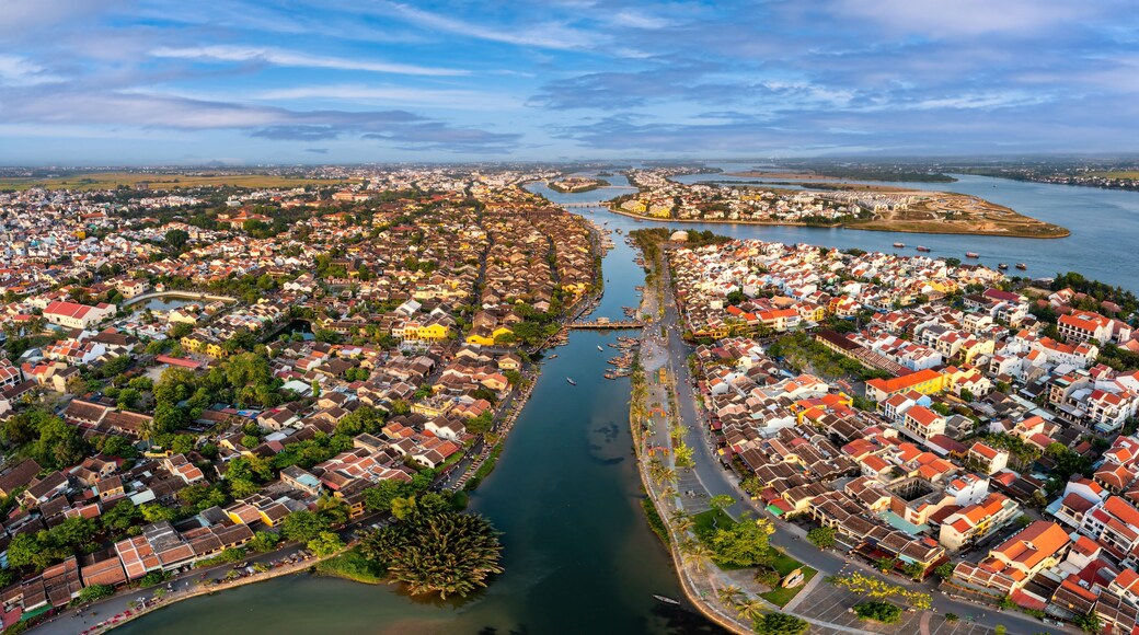 An aerial view of a coastal city with dense housing, a river, and a distant island.