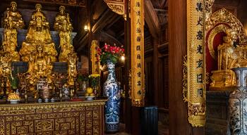 Interior de un templo con estatuas doradas, un jarrón grande y decoraciones ornamentales.