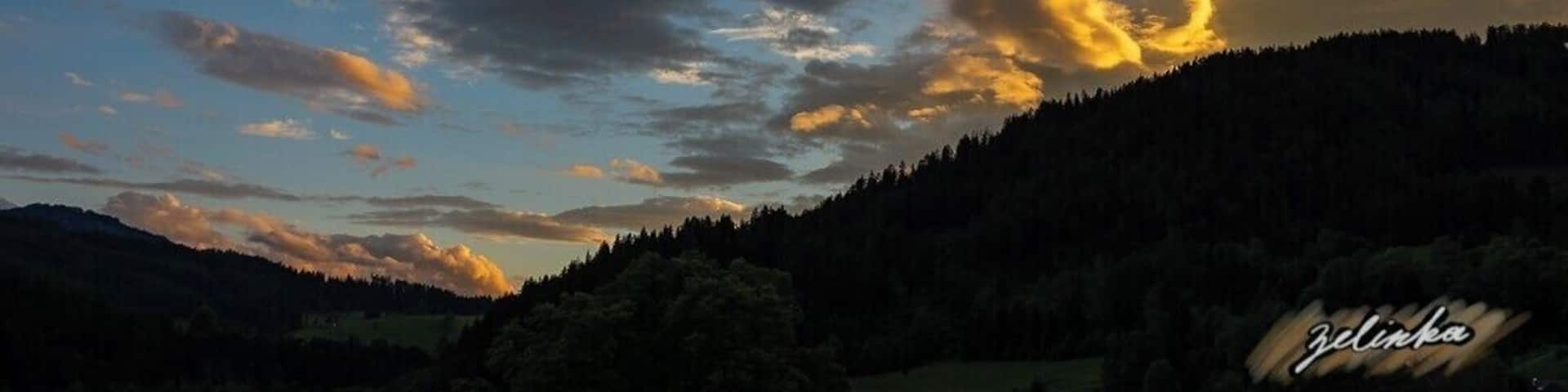 sunset view over the forest covered mountains in a small valley in Austria