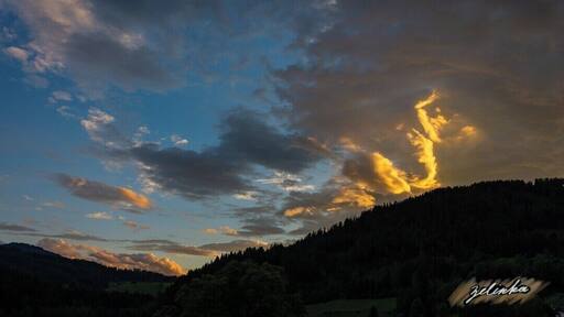 sunset view over the forest covered mountains in a small valley in Austria