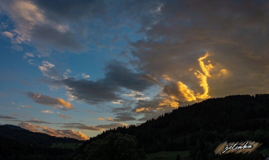 sunset view over the forest covered mountains in a small valley in Austria