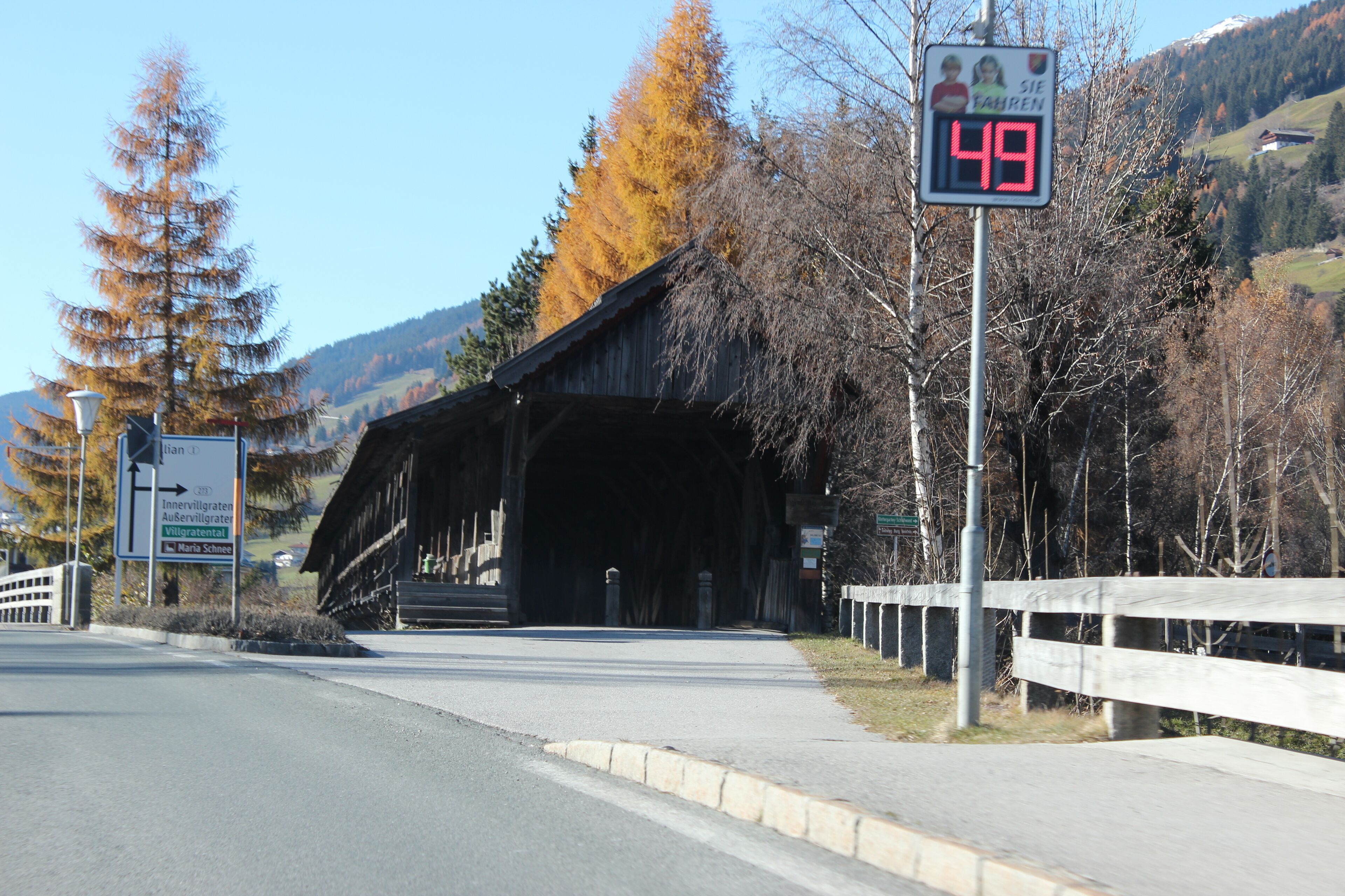 A covered bridge, a speed limit sign, and a directional sign.