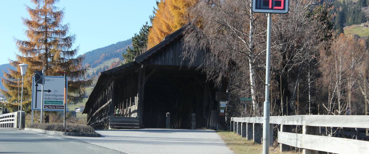 A covered bridge, a speed limit sign, and a directional sign.