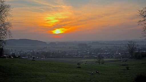 A sunset over a rural landscape with a village in the distance.