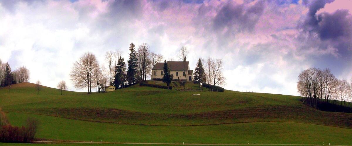 A large house on a hill with a green field in the foreground.