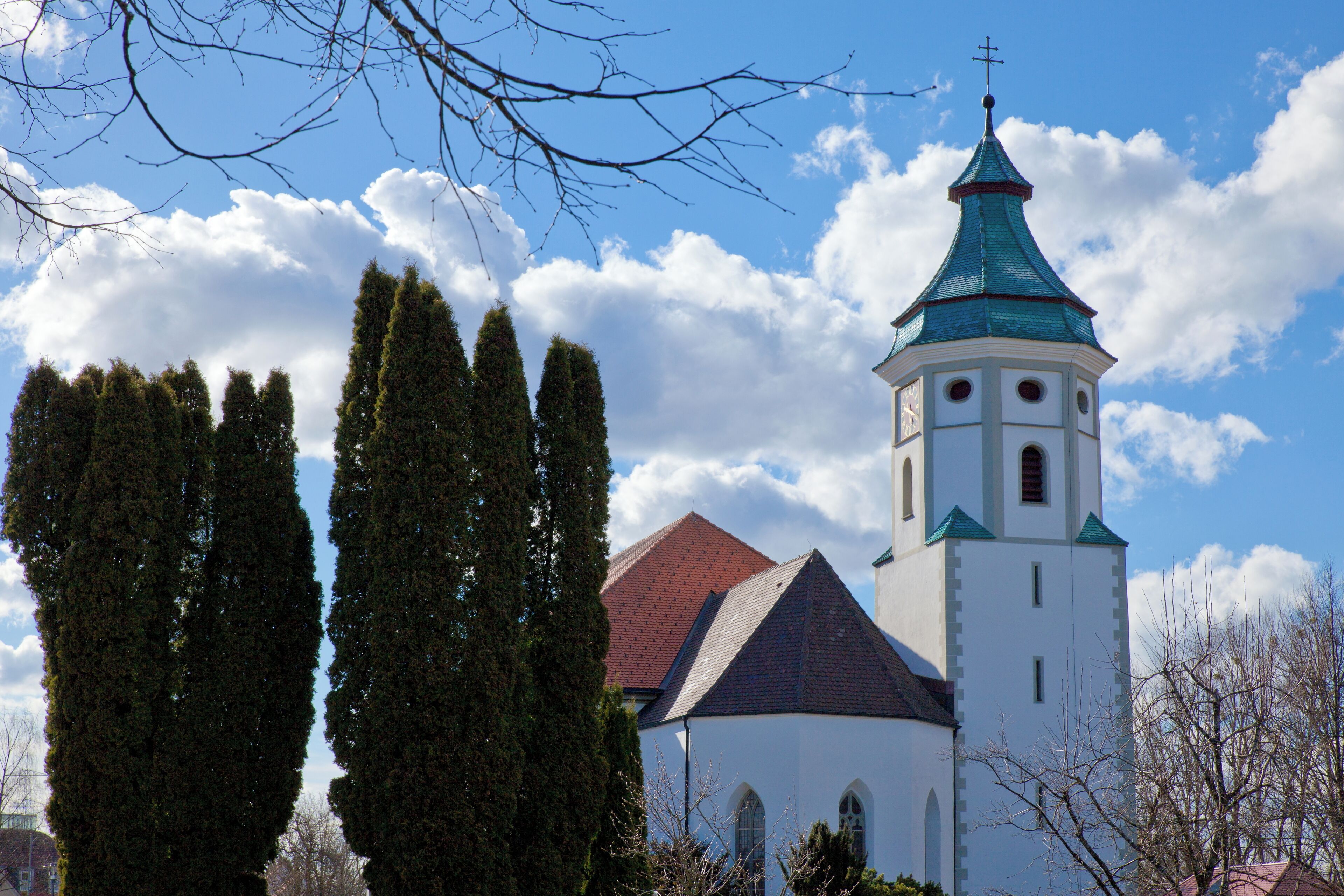 A church with a green spire and white walls.