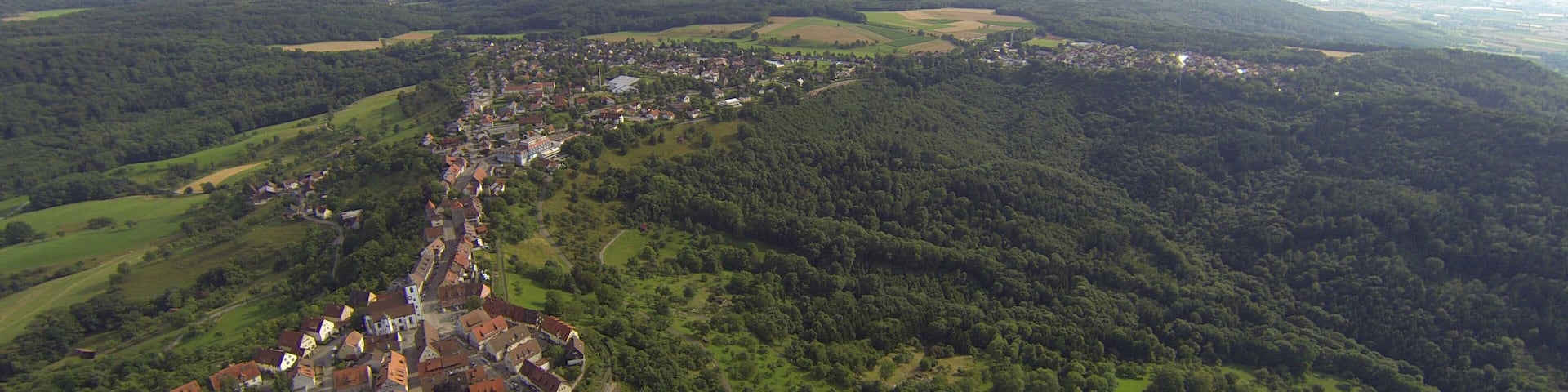 An aerial view of a town nestled in a valley with surrounding forested hills.