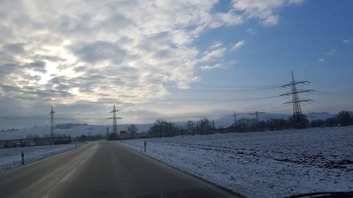 Freileitungen und Umspannwerk (110 kV, mittig verdeckt) nahe dem Richtberg-Werk an der K4946 in Müllheim im Landkreis Breisgau-Hochschwarzwald – links: Bahnstrom mit Abzweigmast (zum Unterwerk Müllheim); Mast rechts: dreikreisige 380-kV-Freileitung Kühmoos–Daxlanden (Gemeinschaftsleitung Amprion/TransnetBW, Bl. 4555)