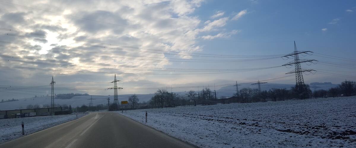 A snow-covered road with power lines and a clear sky.
