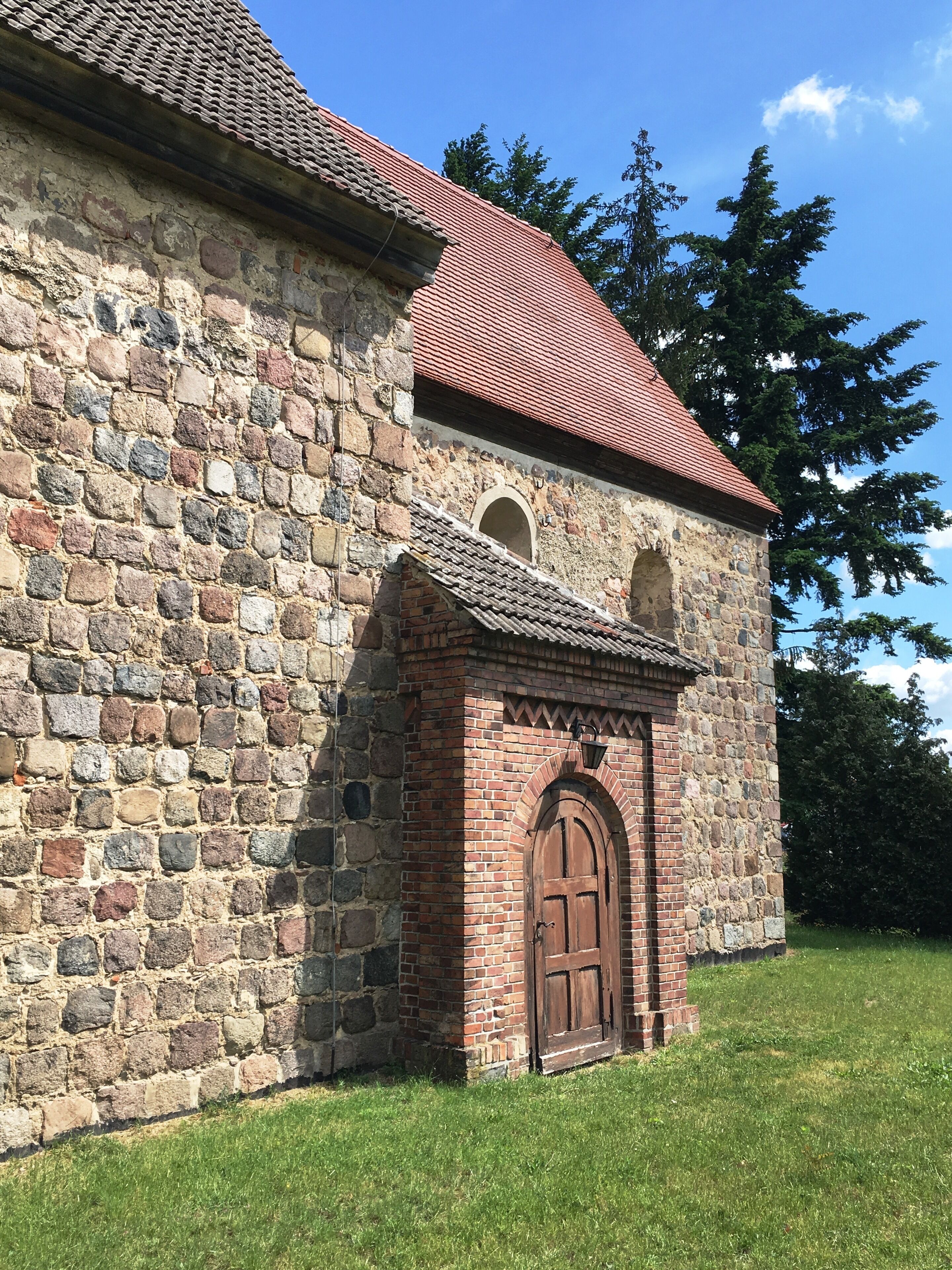 A stone church with a red-tiled roof and a wooden door.