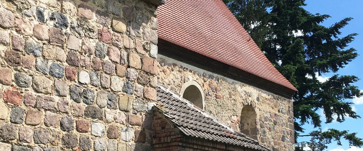 A stone church with a red-tiled roof and a wooden door.