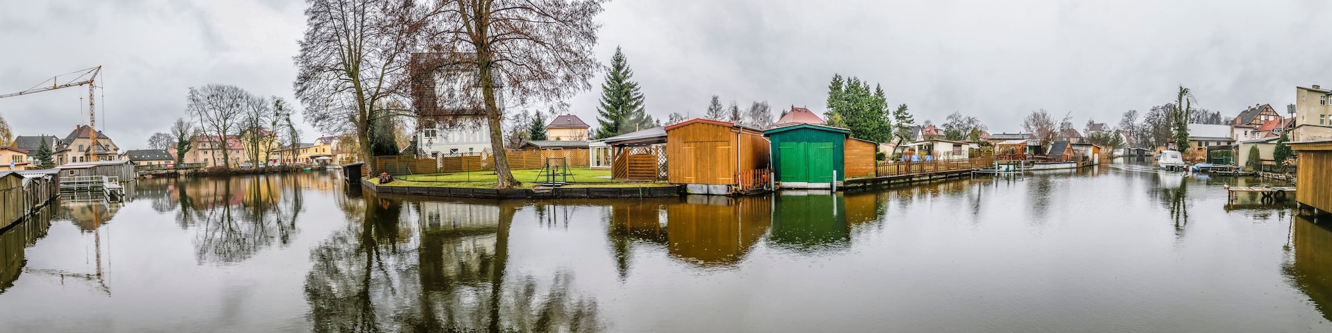 Un canal tranquilo con casas de madera y un cobertizo verde.