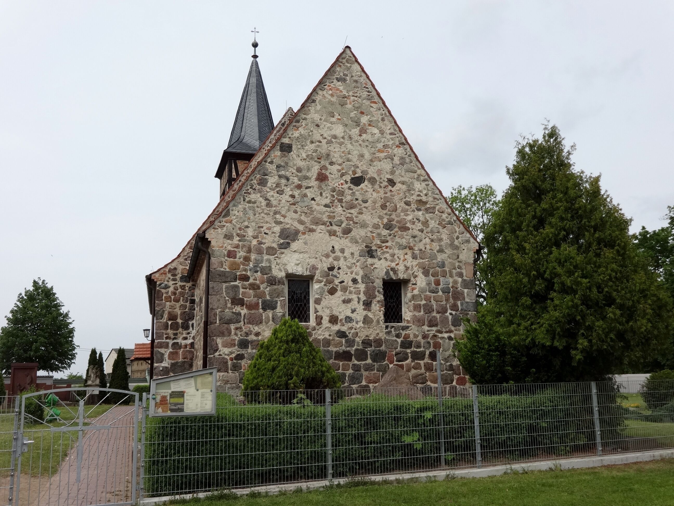 A stone church with a pointed roof and a weather vane.