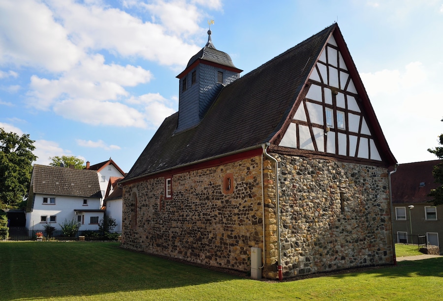 A historic stone building with a steeply pitched roof and a small tower.