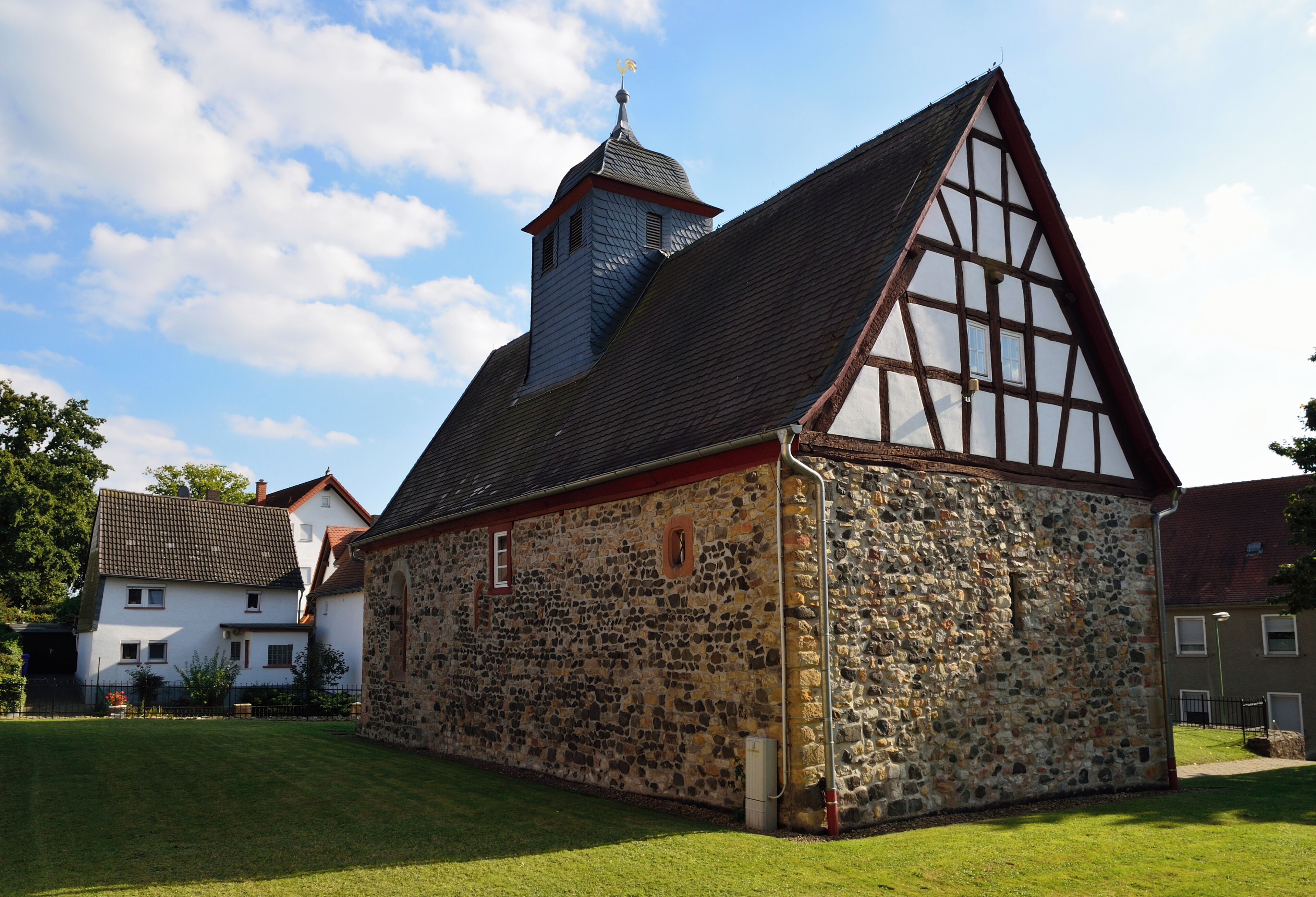 A historic stone building with a steeply pitched roof and a small tower.