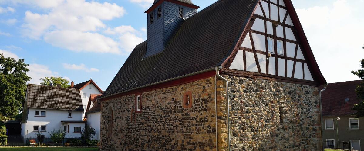A historic stone building with a steeply pitched roof and a small tower.