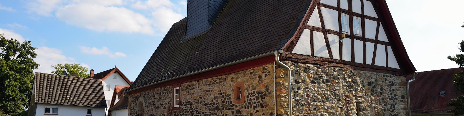 A historic stone building with a steeply pitched roof and a small tower.