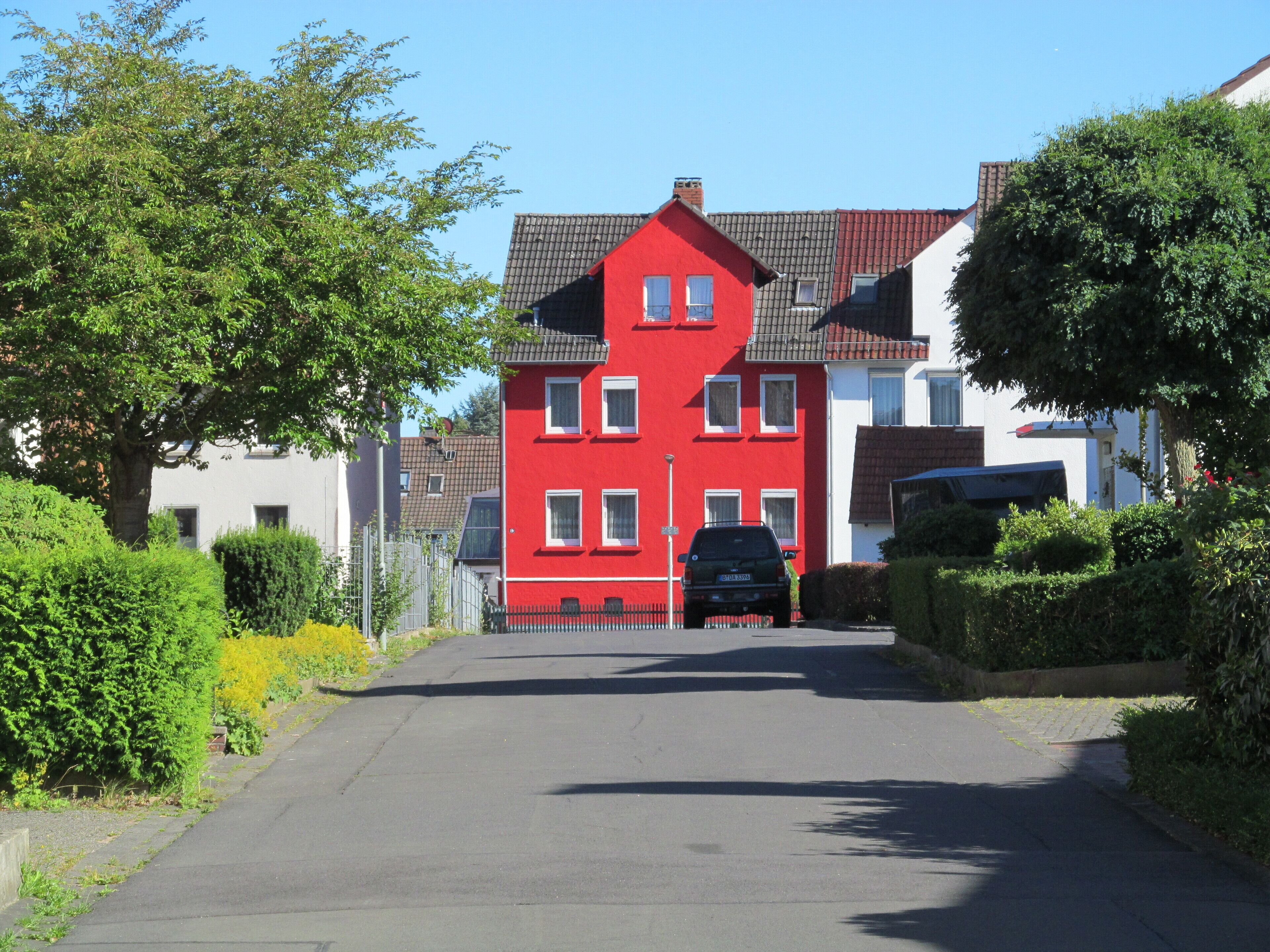 A red house with a black car parked in front.