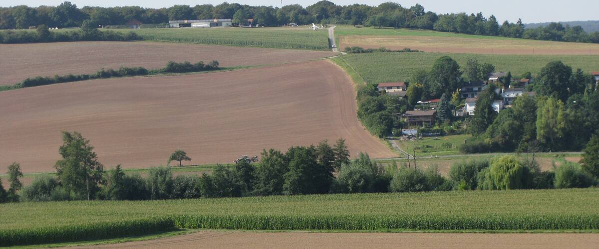 A rural landscape with fields, a windmill, and a small village.