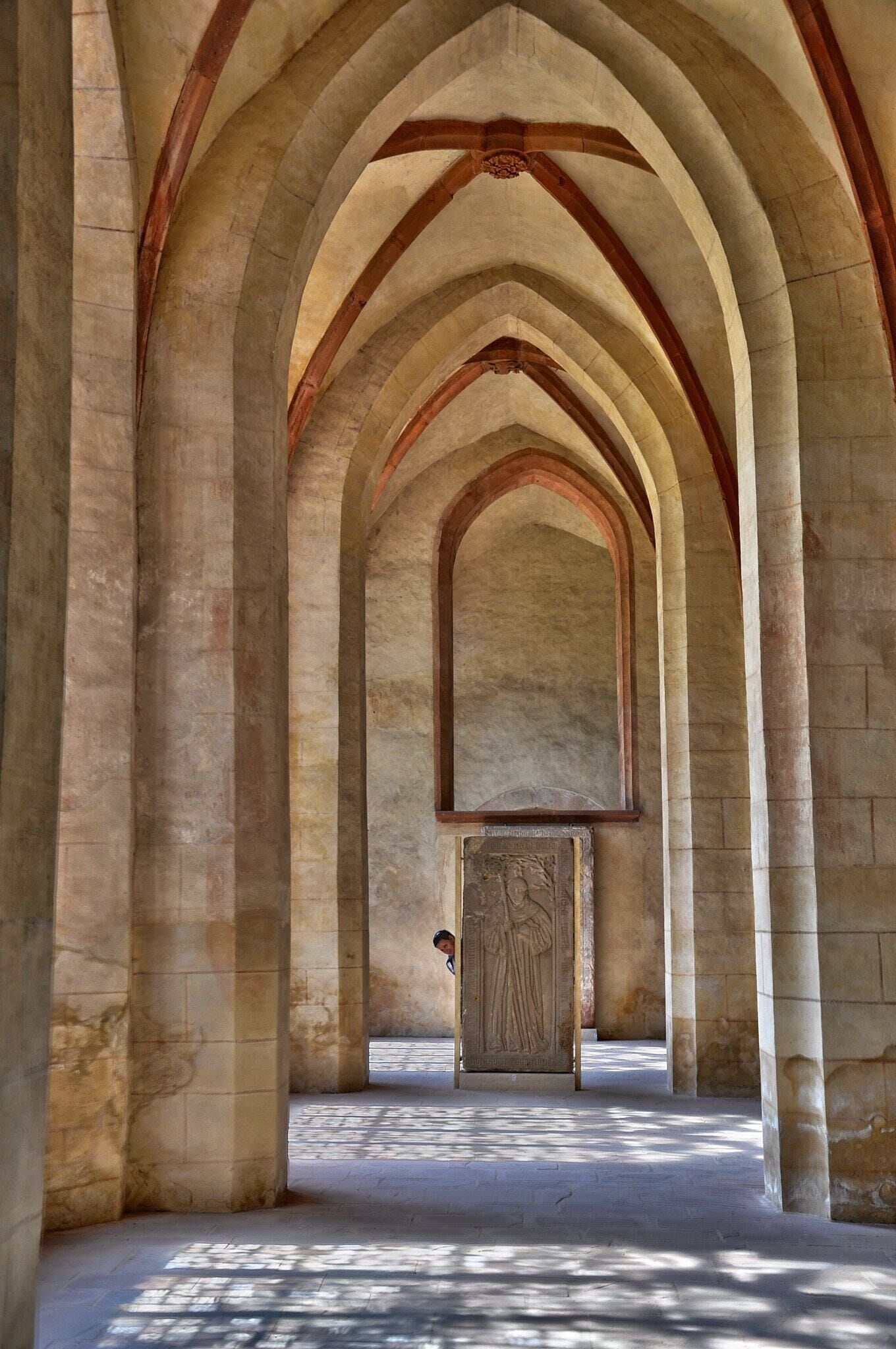 An arched corridor with stone columns and a wooden door at the end.