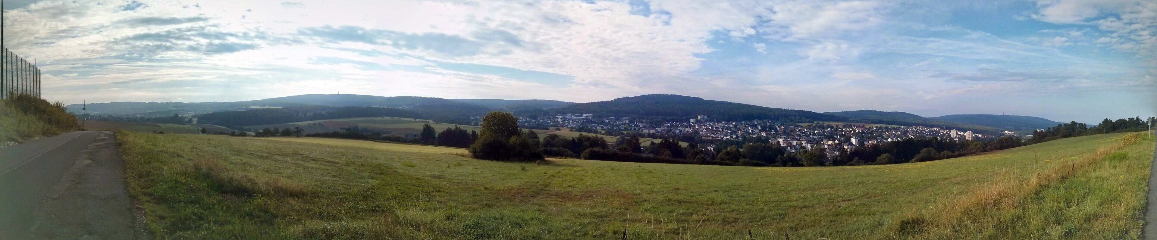A rural landscape with rolling hills, a road, and a distant town.