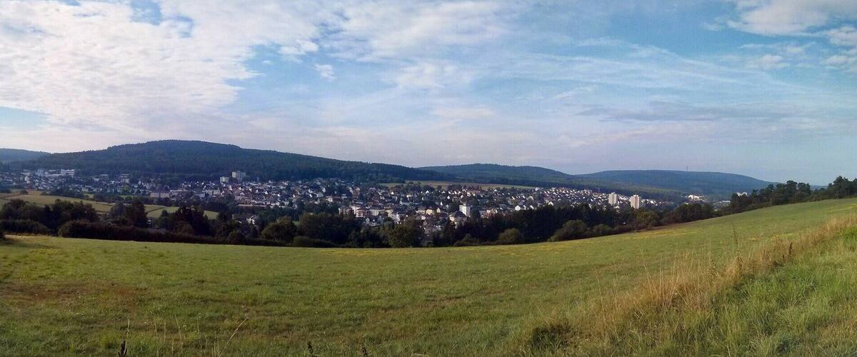 A rural landscape with rolling hills, a road, and a distant town.