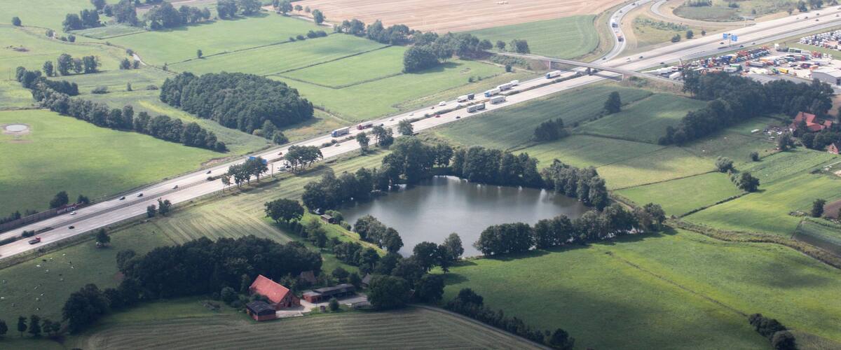 An aerial view of a rural landscape with fields, a lake, and a highway.