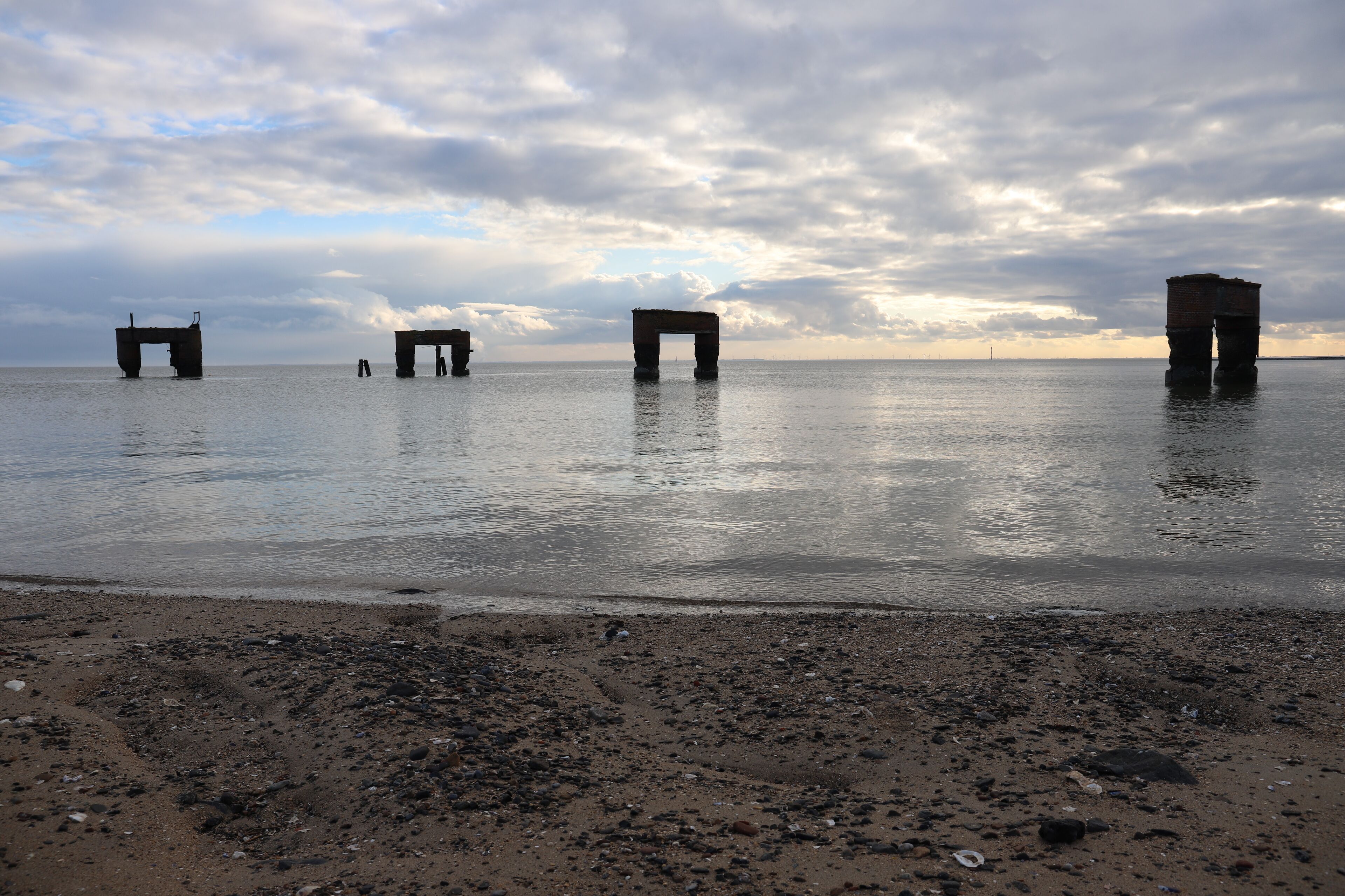 A beach with three large stone structures in the water.