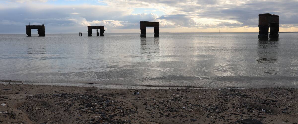 A beach with three large stone structures in the water.