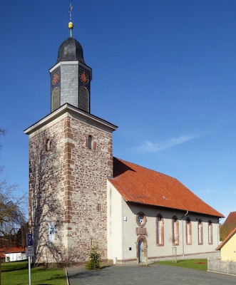 Eine Kirche mit einem Steinturm und einem roten Ziegeldach.