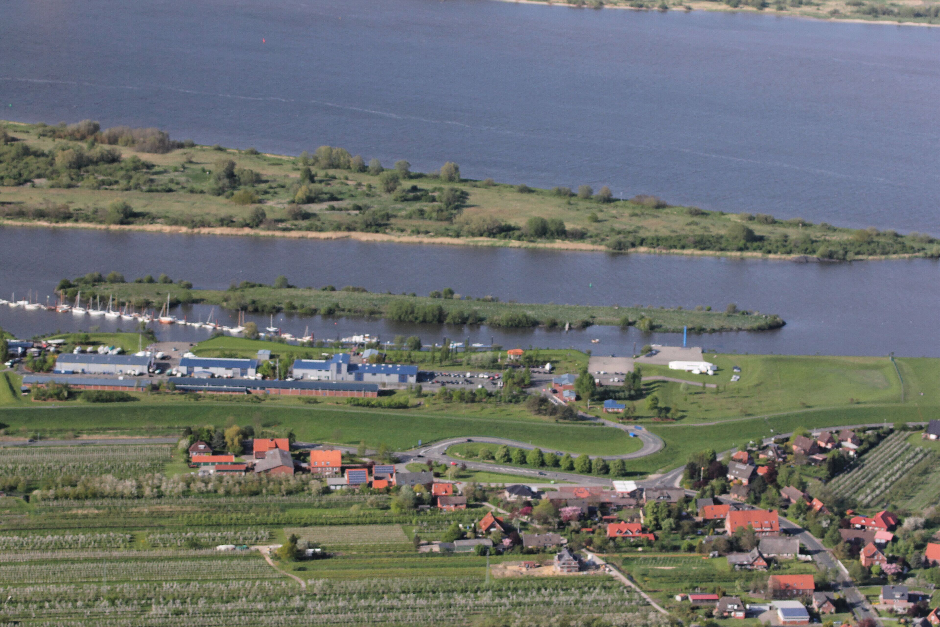 A lakeside village with boats, houses, and agricultural fields.